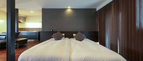A modern hotel room with a large bed, a desk, and a view of the city.