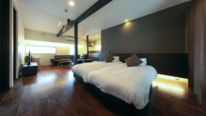 A modern bedroom with a large bed, wooden flooring, and a dark accent wall.