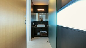 A hallway leading to a bathroom with a modern design, including a sink and mirror.