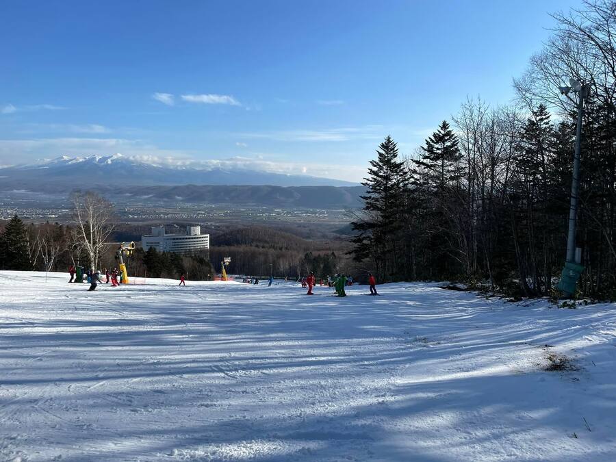 A snowy ski slope with skiers and a mountain in the background.
