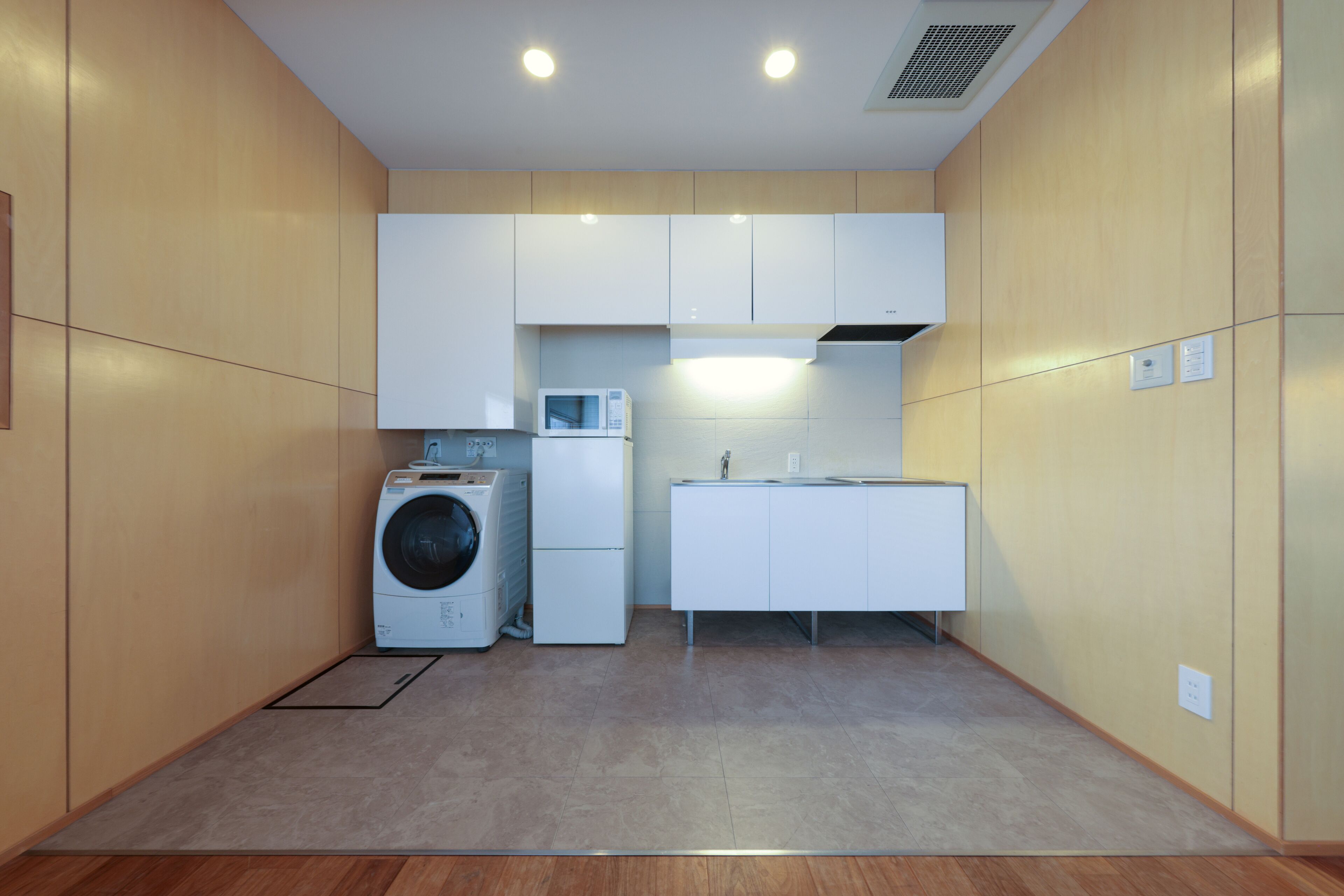 A compact kitchen with a washing machine, a microwave, and a sink.