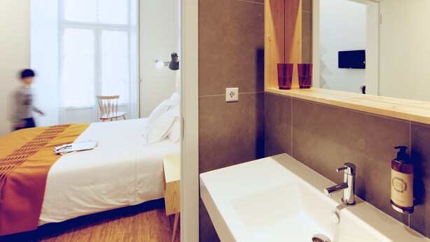 A modern hotel room with a bed, bedside table, and a large mirror above the sink. - Hall Chiado (Lisbon)