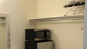 A compact kitchenette with a stainless steel refrigerator, a microwave, and a small countertop. - American Travel Inn (Pullman)