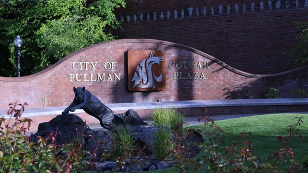 A sign for the City of Pullman Cougar Plaza with a cougar statue and a brick wall. - American Travel Inn (Pullman)