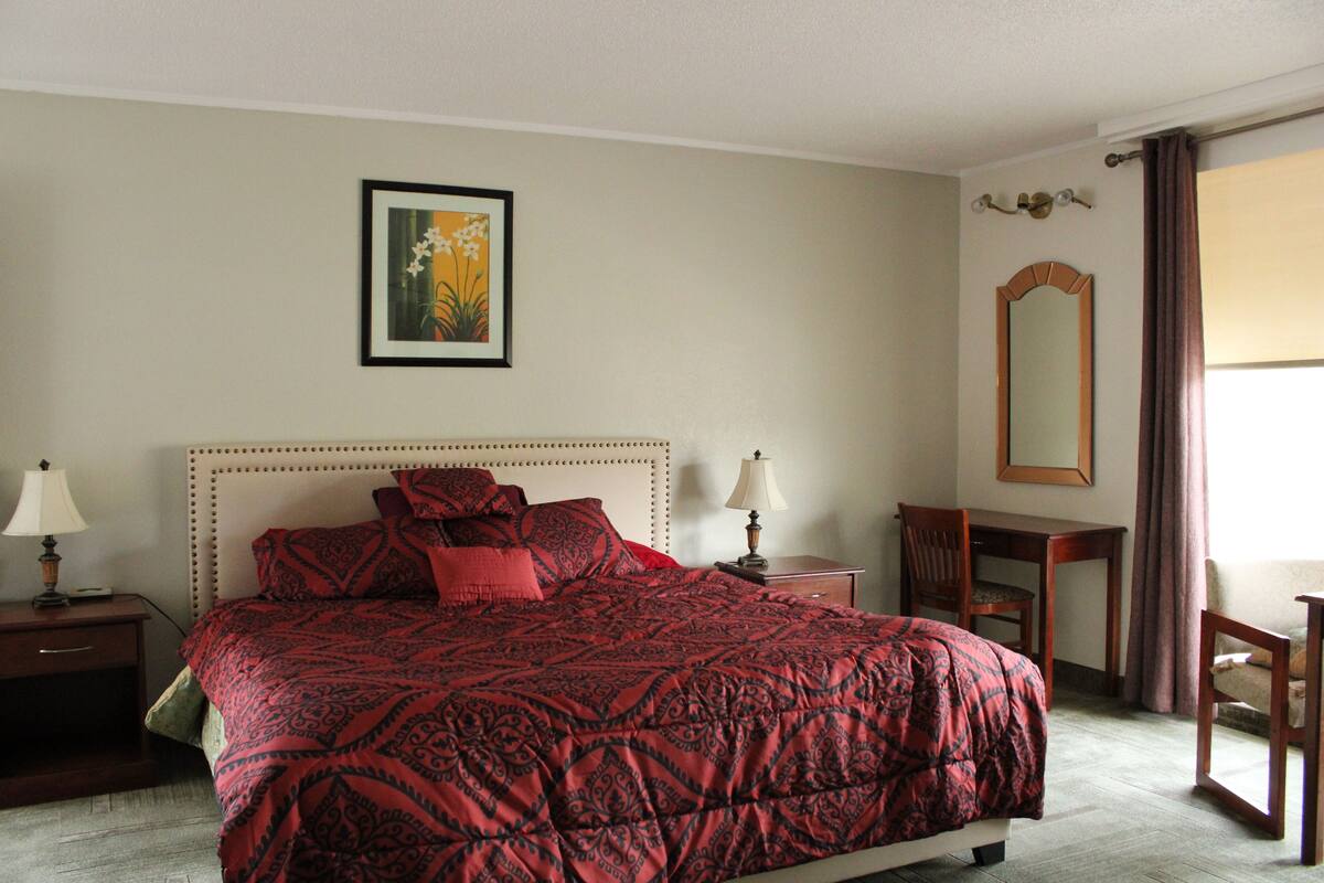 A neatly arranged hotel room with a large bed, a desk, and a chair.