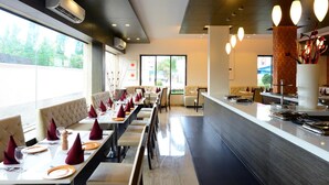 Un restaurant moderne avec de longues tables, des sièges confortables et un bar central.