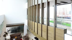 Un intérieur moderne avec une cheminée, un coin salon et une grande fenêtre donnant sur un espace extérieur.