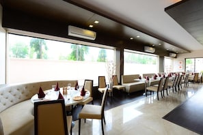 A restaurant with a long counter, booths, and tables with red napkins. - JC Castle (Rahata)