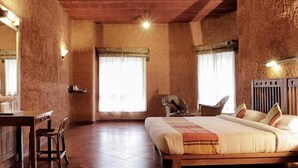 Un dormitorio con cama de madera, un escritorio y sillas, con un ventanal grande y un radiador.