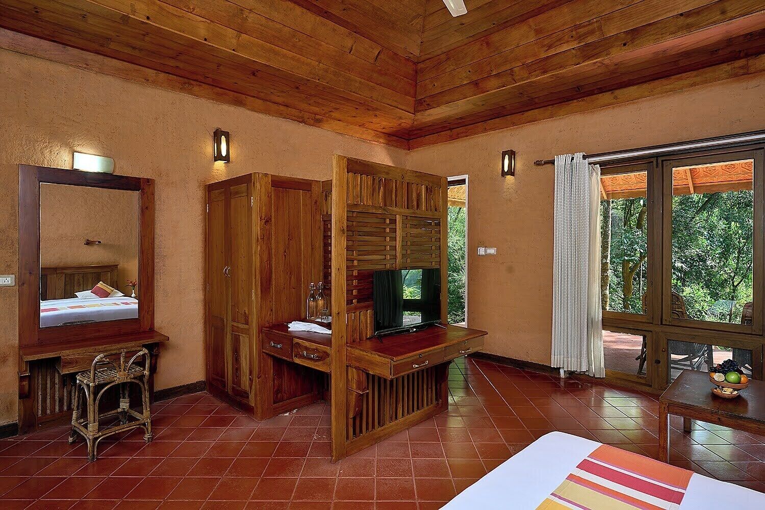 Una habitación con paneles de madera, una cama, un televisor y una ventana con vista a follaje.