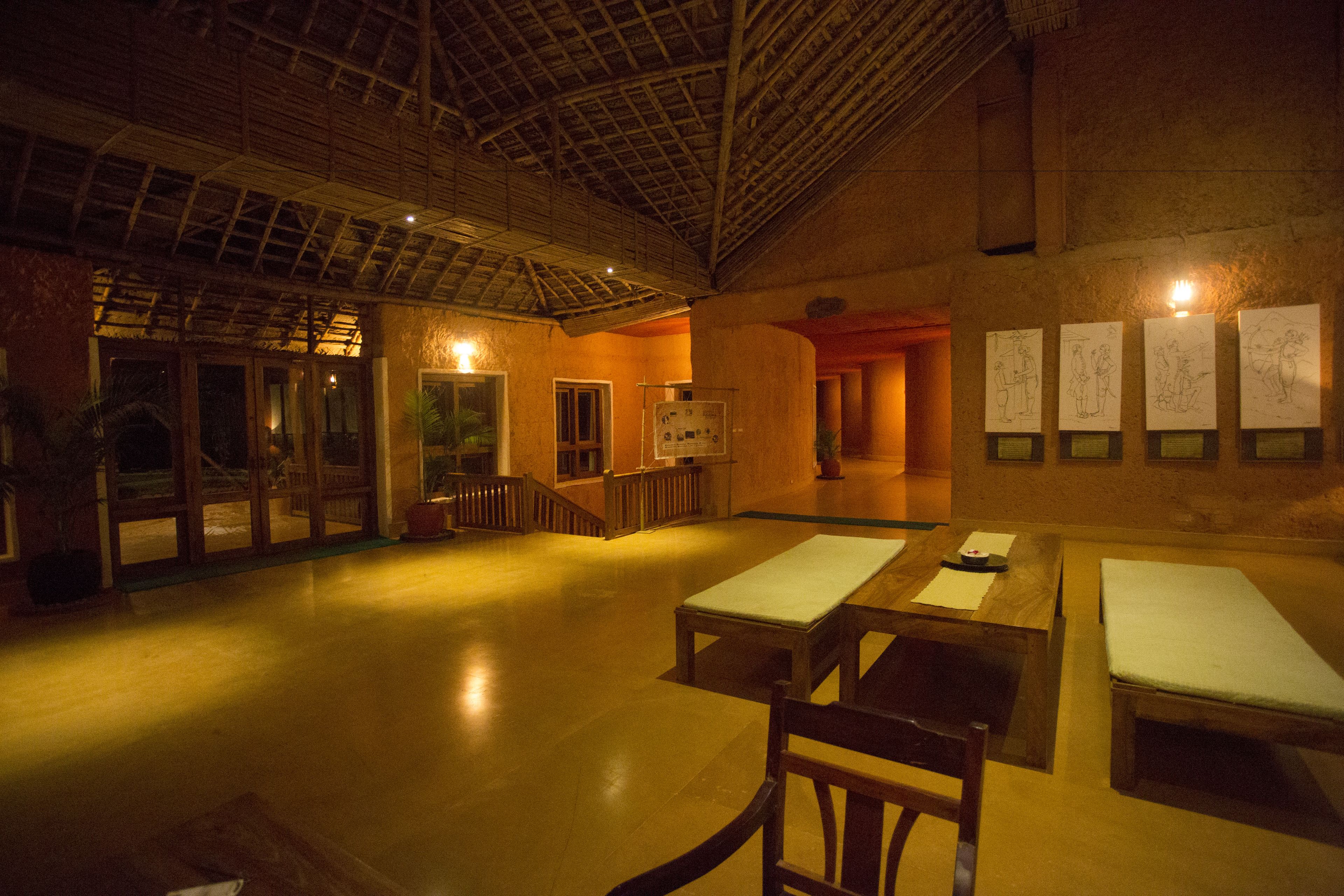 An indoor space with a high ceiling, wooden benches, and a staircase.