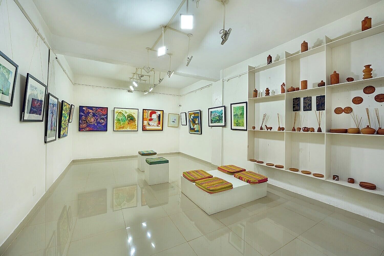 Una galería de arte con pinturas en las paredes y estantes con cerámica.