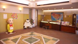 Un vestíbulo de hotel con una recepción, un gran tapete decorativo, una estatua de oso polar y un cuadro abstracto colorido en la pared.