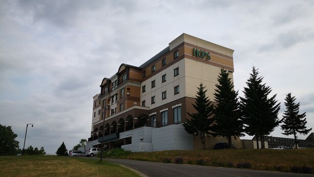 Un hotel de varios pisos con un llamativo letrero de 'Hops', que presenta un diseño arquitectónico moderno con balcones y techo plano.