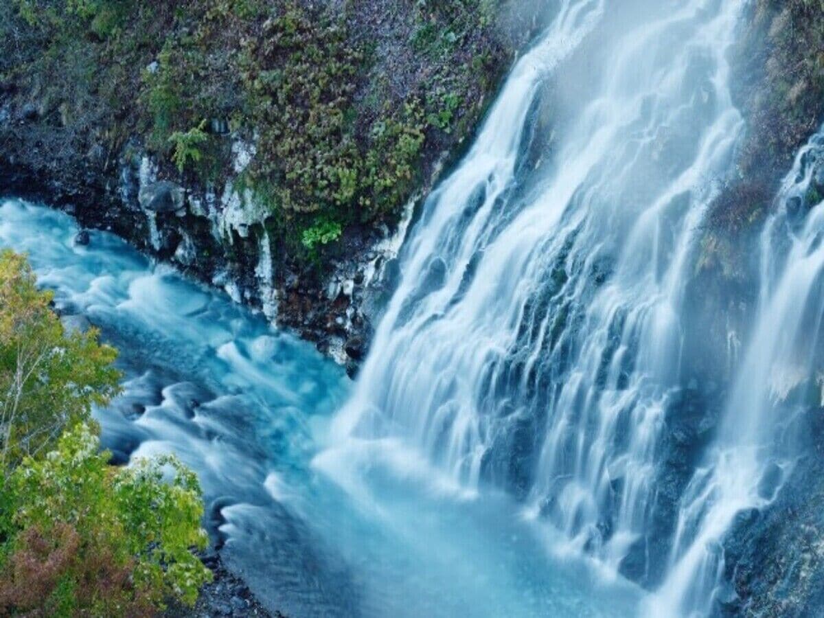 A waterfall cascading down a rocky cliff surrounded by greenery.