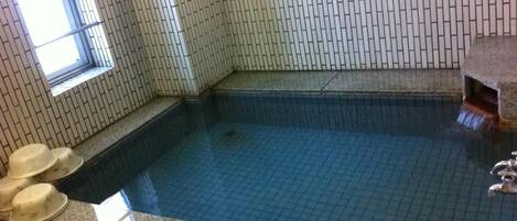 En lille indendørs swimmingpool med flisebeklædte vægge og gulv.