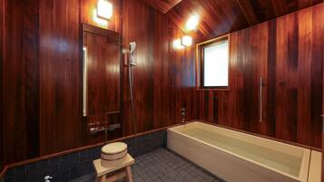 Un baño revestido de paneles de madera con una bañera grande, un taburete de madera y un espejo.