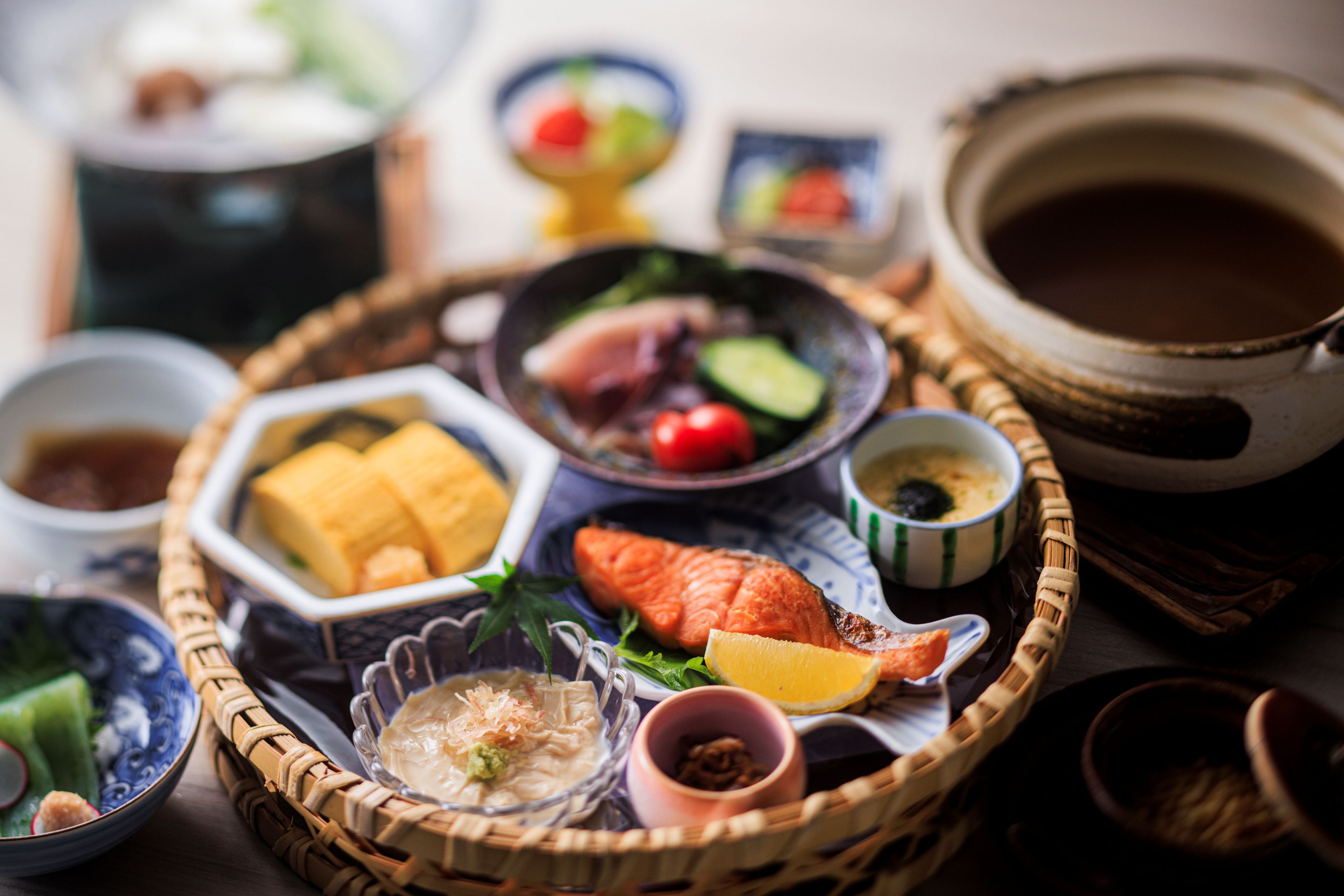 A traditional Japanese meal with various dishes and bowls on a woven tray.