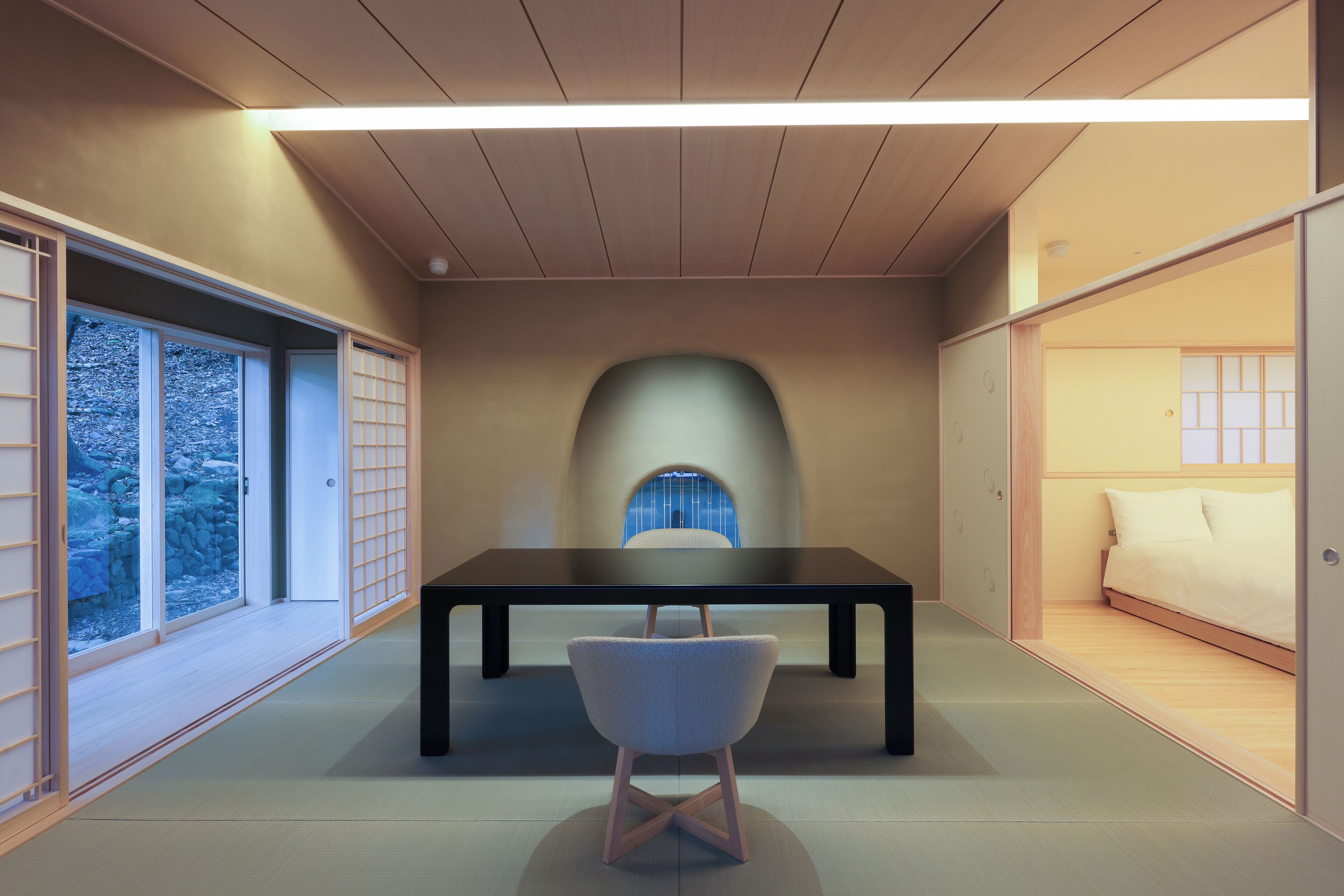 A traditional Japanese-style room with tatami flooring, a low table, and a cushioned chair.