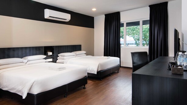 Una habitación de hotel con dos camas, un escritorio, un televisor y una ventana con cortinas.