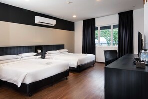 A hotel room with two beds, a desk, a TV, and a window with curtains.