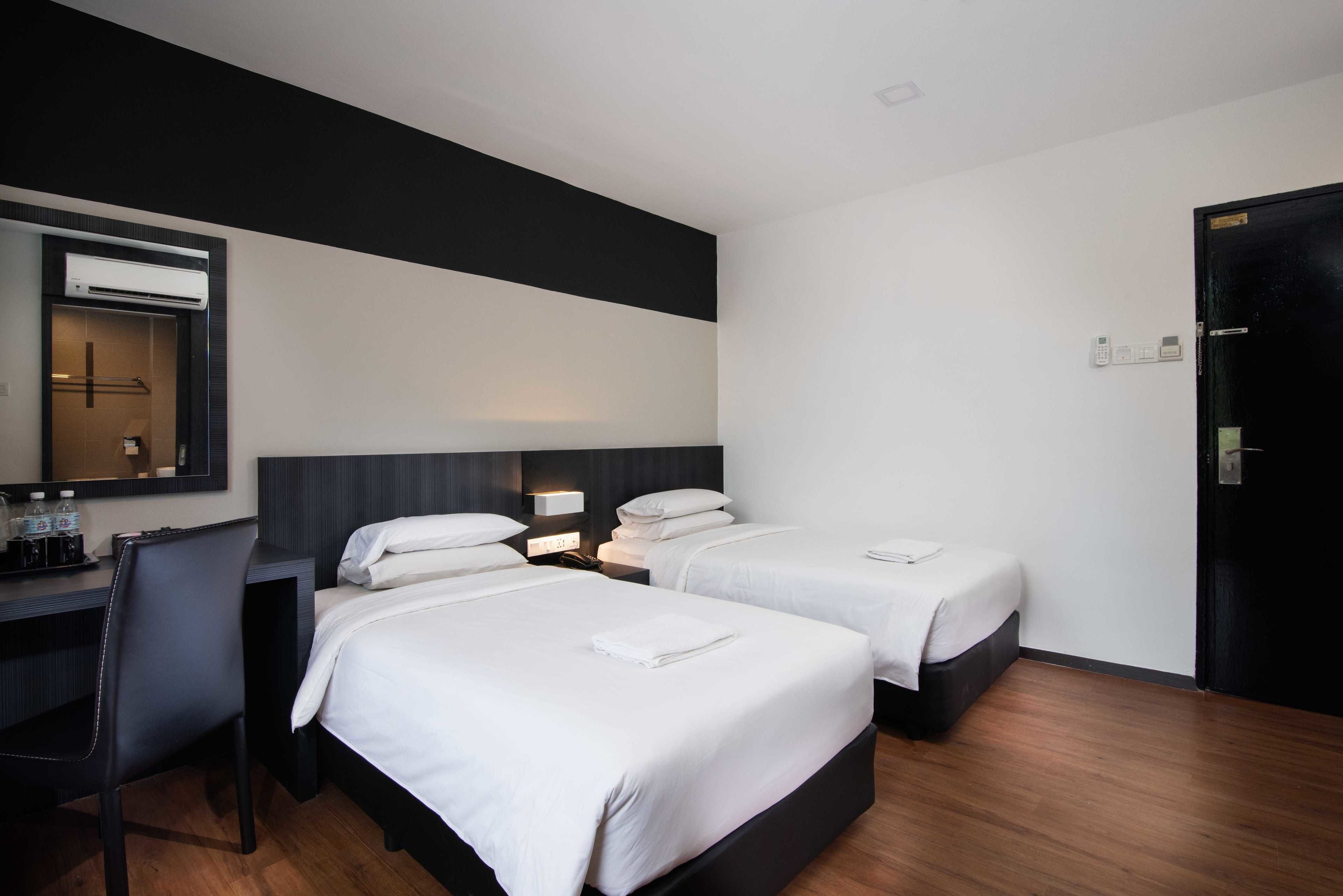 A hotel room with two beds, a desk, a chair, and a wardrobe.