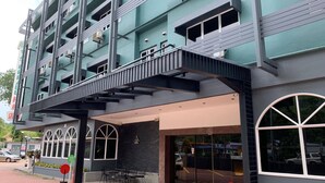 Un edificio de varios pisos con un diseño moderno, que cuenta con un acceso cubierto y zona de estar al aire libre.