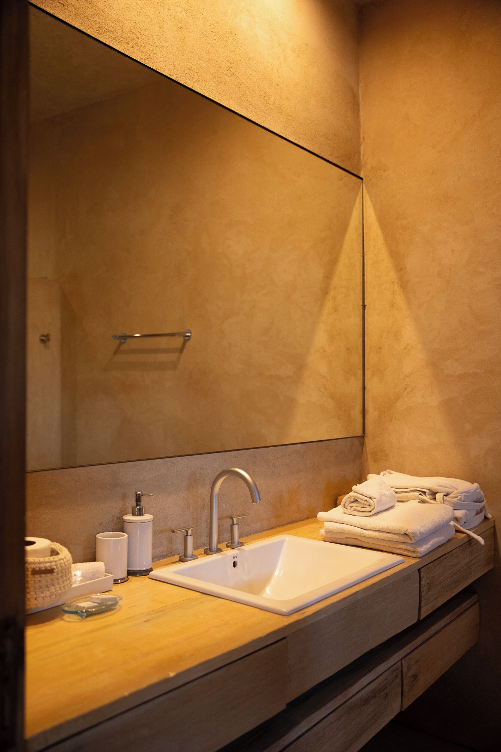 A bathroom with a sink, mirror, towel rack, and toiletries.