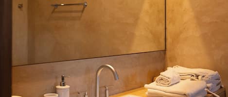A bathroom with a sink, mirror, towel rack, and toiletries.
