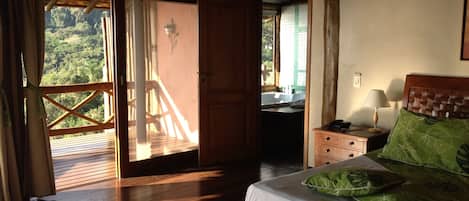 Un dormitorio con una cama de madera, una mesita de noche y vistas a un balcón con barandilla de madera.
