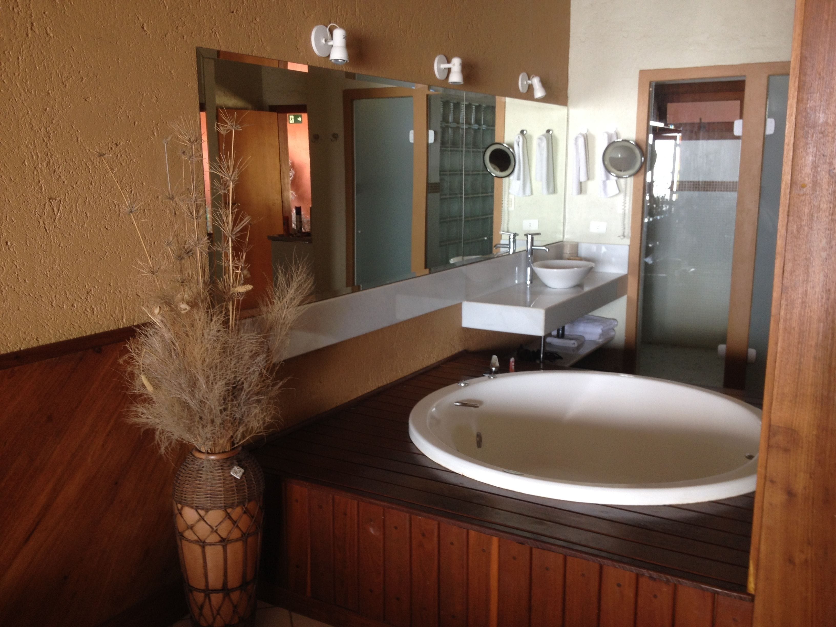A bathroom with a wooden vanity, a white sink, and a large mirror.