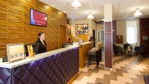 Ein Hotel-Empfangsbereich mit modernem Design, inklusive einer Rezeption, einer Bar und Sitzgelegenheiten für Gäste.