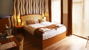 Ein Hotelzimmer mit Bett, Nachttischen, Fernseher und einem Fenster mit Vorhängen.