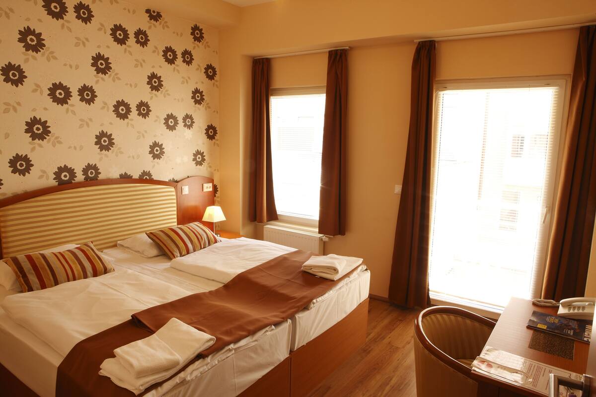 A hotel room with a large bed, a desk with a telephone, and a chair.