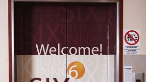 Eine Aufzugtür mit der Aufschrift "Welcome! SIX INN BUDAPEST" und einem Verbotsschild für Rauchen.