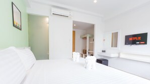 A hotel room with a large bed, a TV mounted on the wall, and a door leading to a bathroom. - The Frutta Boutique Patong Beach (Patong)