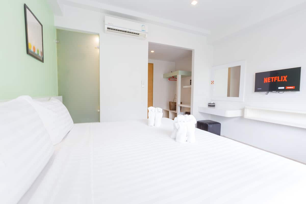 Ein Hotelzimmer mit einem großen Bett, einem an der Wand befestigten Fernseher und einer Tür zu einem Badezimmer.