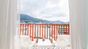 A balcony with white chairs and a table, offering a view of a cityscape and mountains. - The Frutta Boutique Patong Beach (Patong)