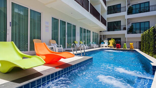 A swimming pool with multiple slides, surrounded by lounge chairs and a multi-story building with balconies. - The Frutta Boutique Patong Beach (Patong)