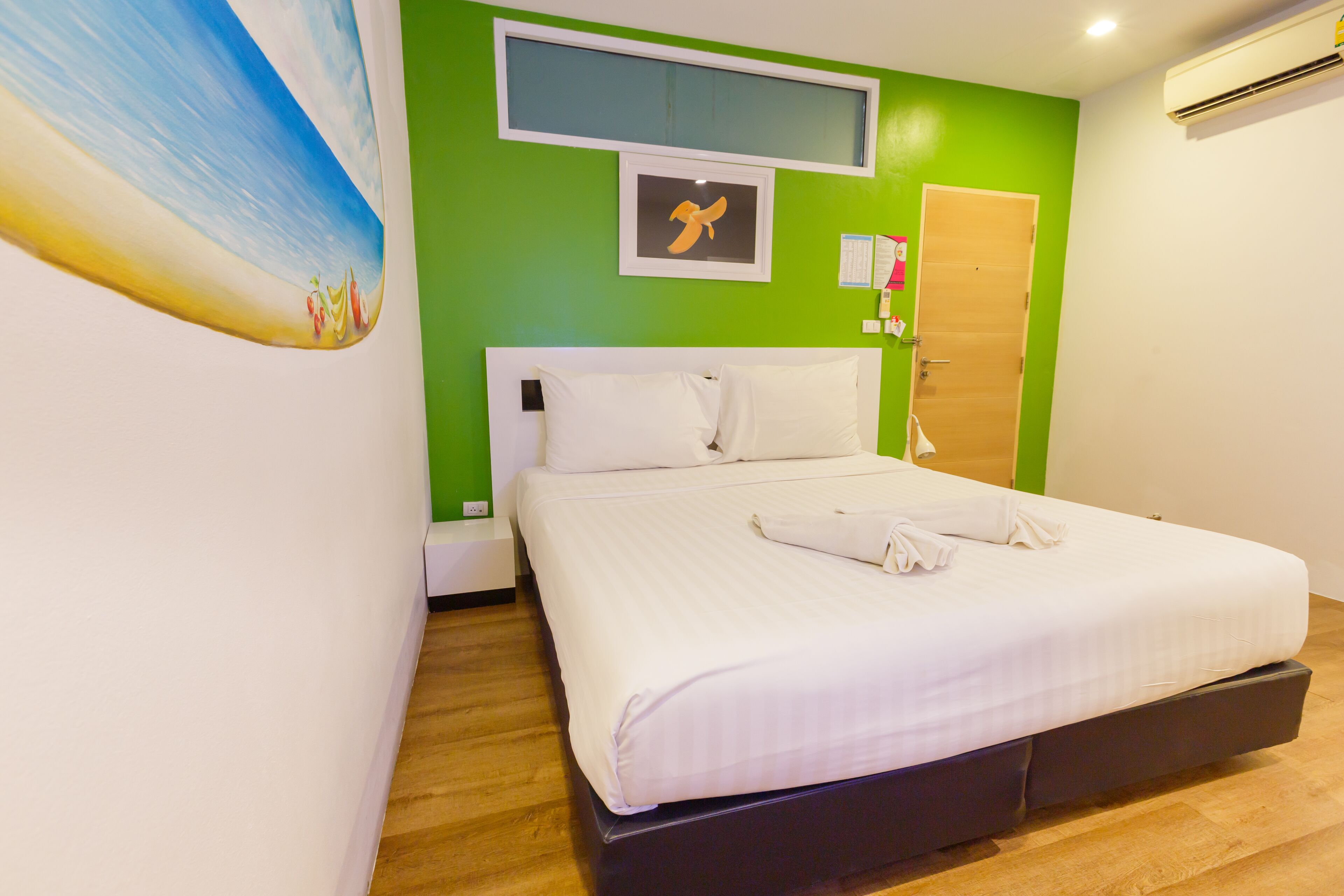 A bedroom with a bed, green walls, a painting, and a door.