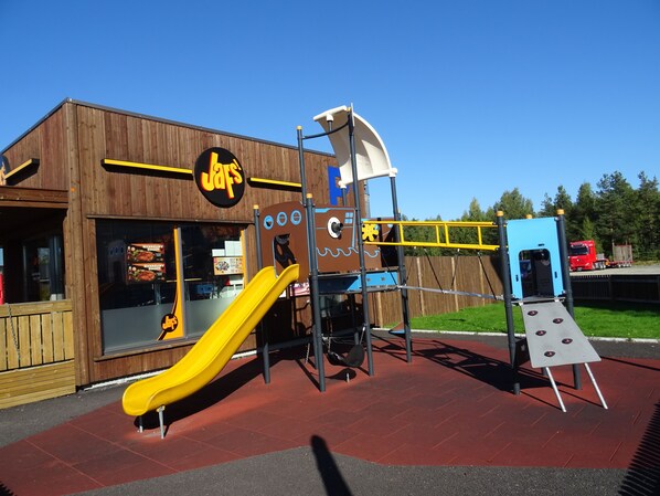 A playground with a yellow slide, climbing structures, and a blue playhouse. - Thon Hotel Elgstua (Elverum)