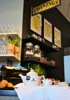 Un desayuno con té Twinings, croissants y una tetera sobre una mesa.