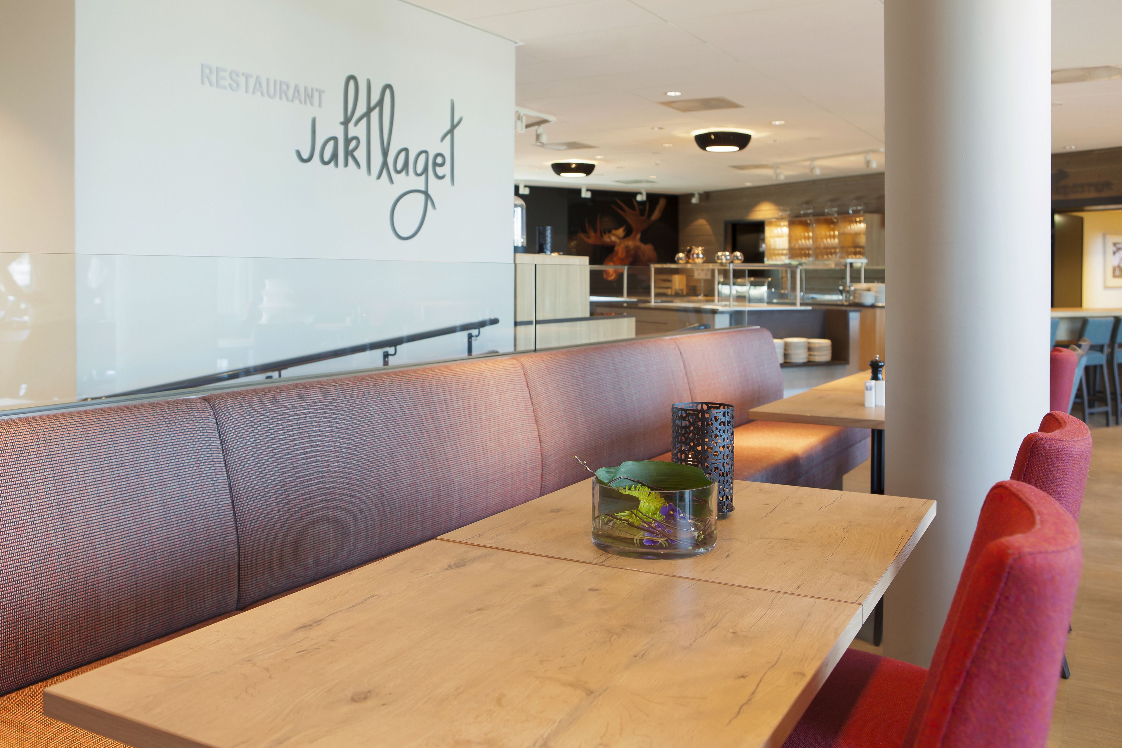 En restaurantindretning med et træbord, en bænk og en dekorativ glasbeholder.
