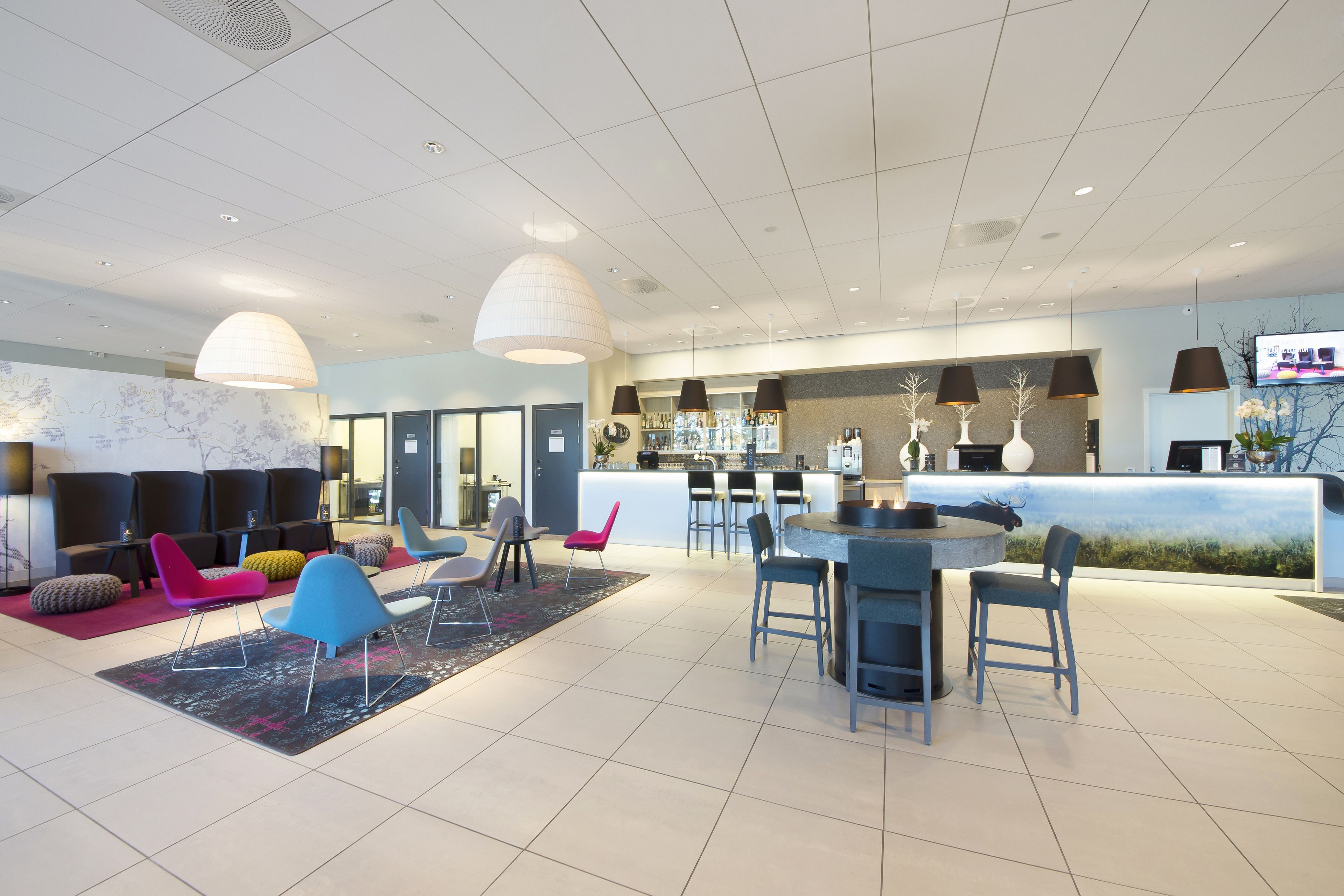 A modern lobby with a reception desk, seating area, and a bar.