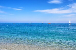 A clear blue sea with boats and a sandy beach.