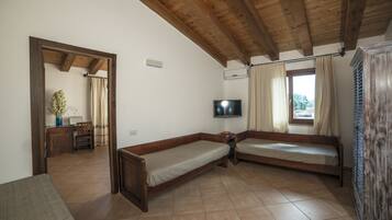 A room with two wooden beds, a TV, and a window with curtains.