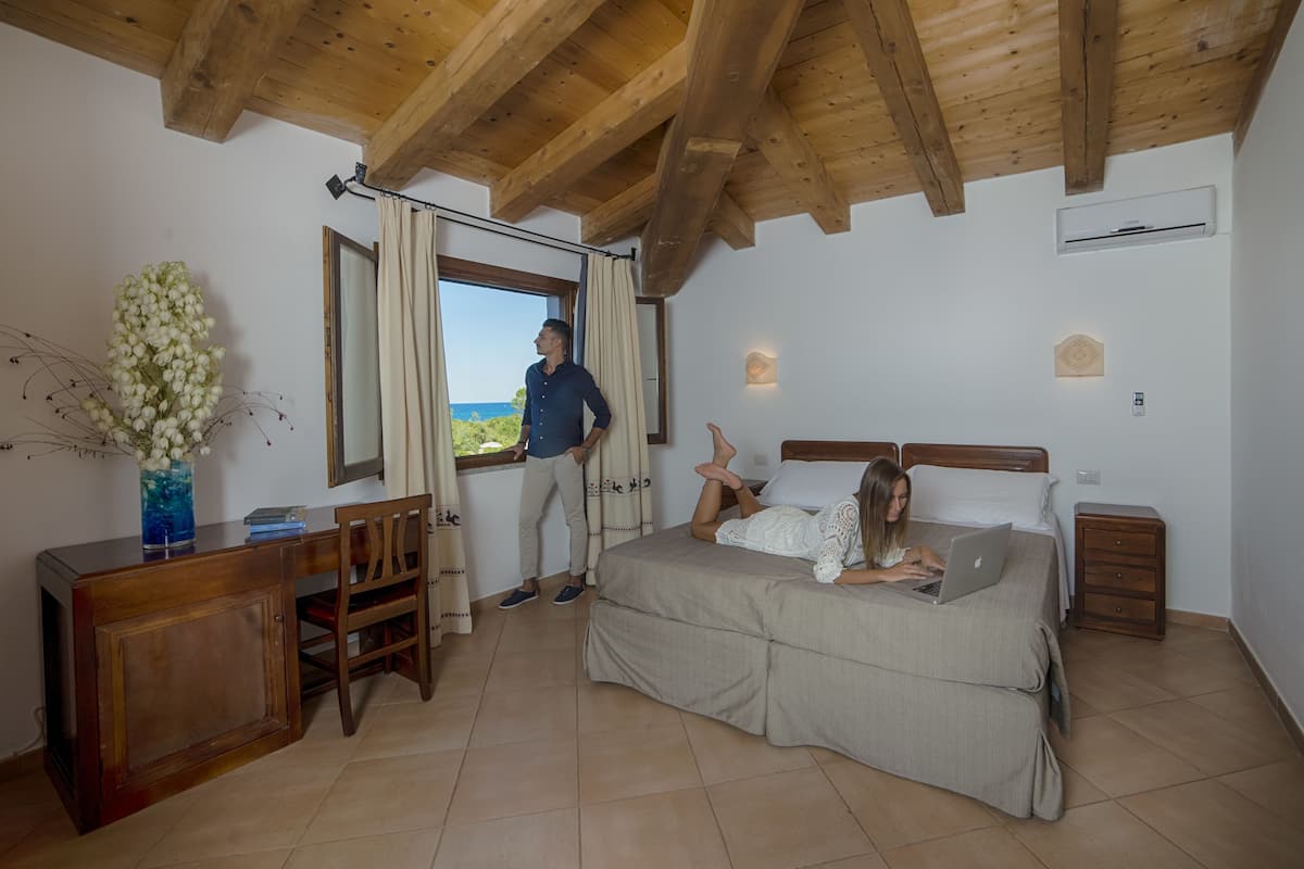 Ein Schlafzimmer mit einem Bett, einem Schreibtisch, einem Stuhl und einem Fenster mit Vorhängen.
