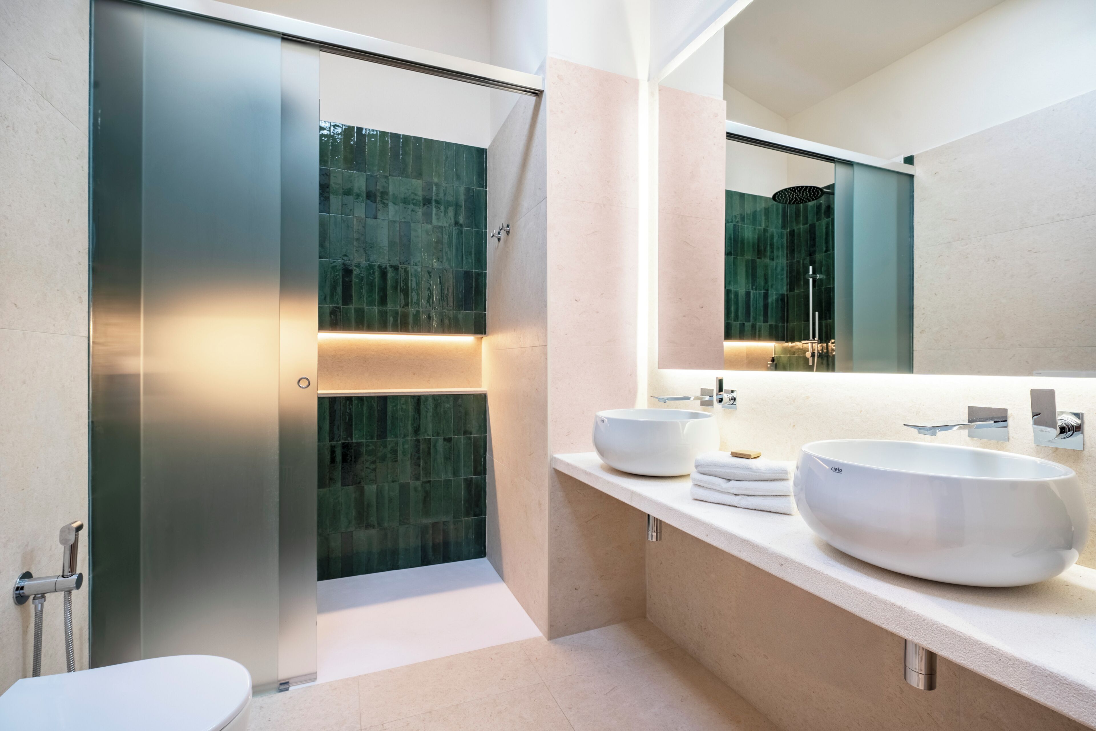 A modern bathroom with a glass shower enclosure, two large sinks, and a large mirror.