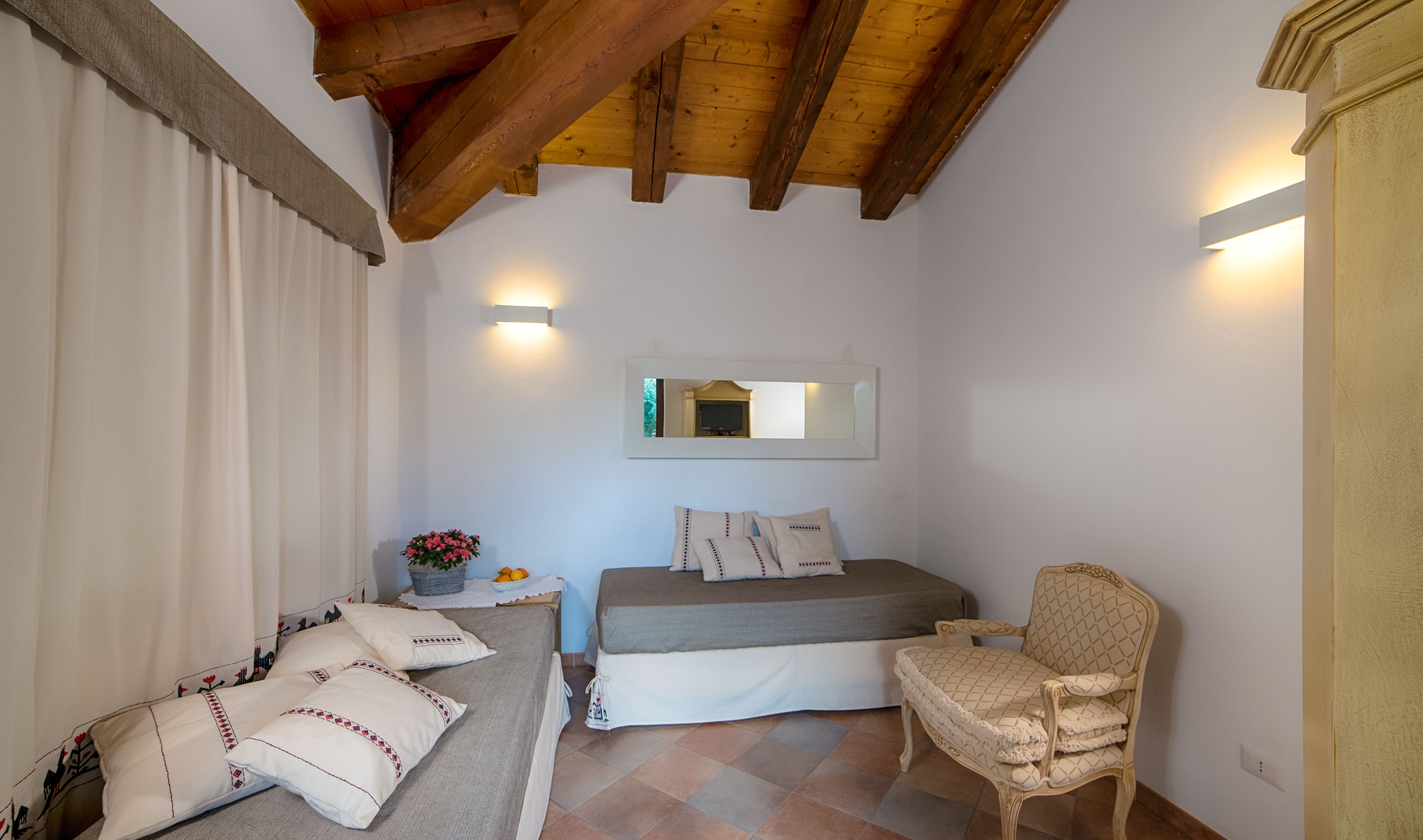 Une chambre à coucher avec un lit, une chaise, une table de chevet avec une lampe et un miroir au mur.