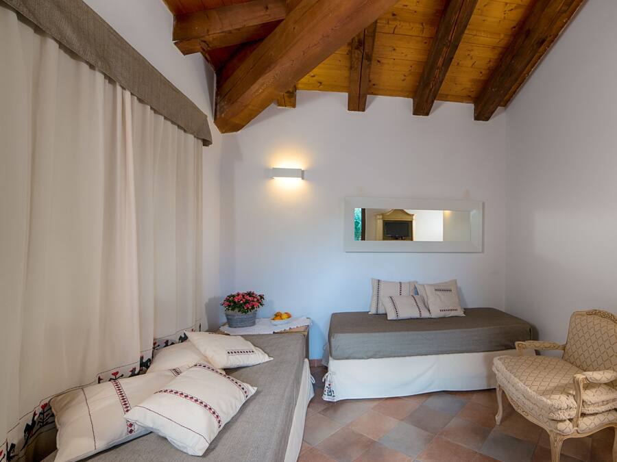 Une chambre à coucher avec un lit, une chaise, une table de chevet avec une lampe et un miroir au mur.